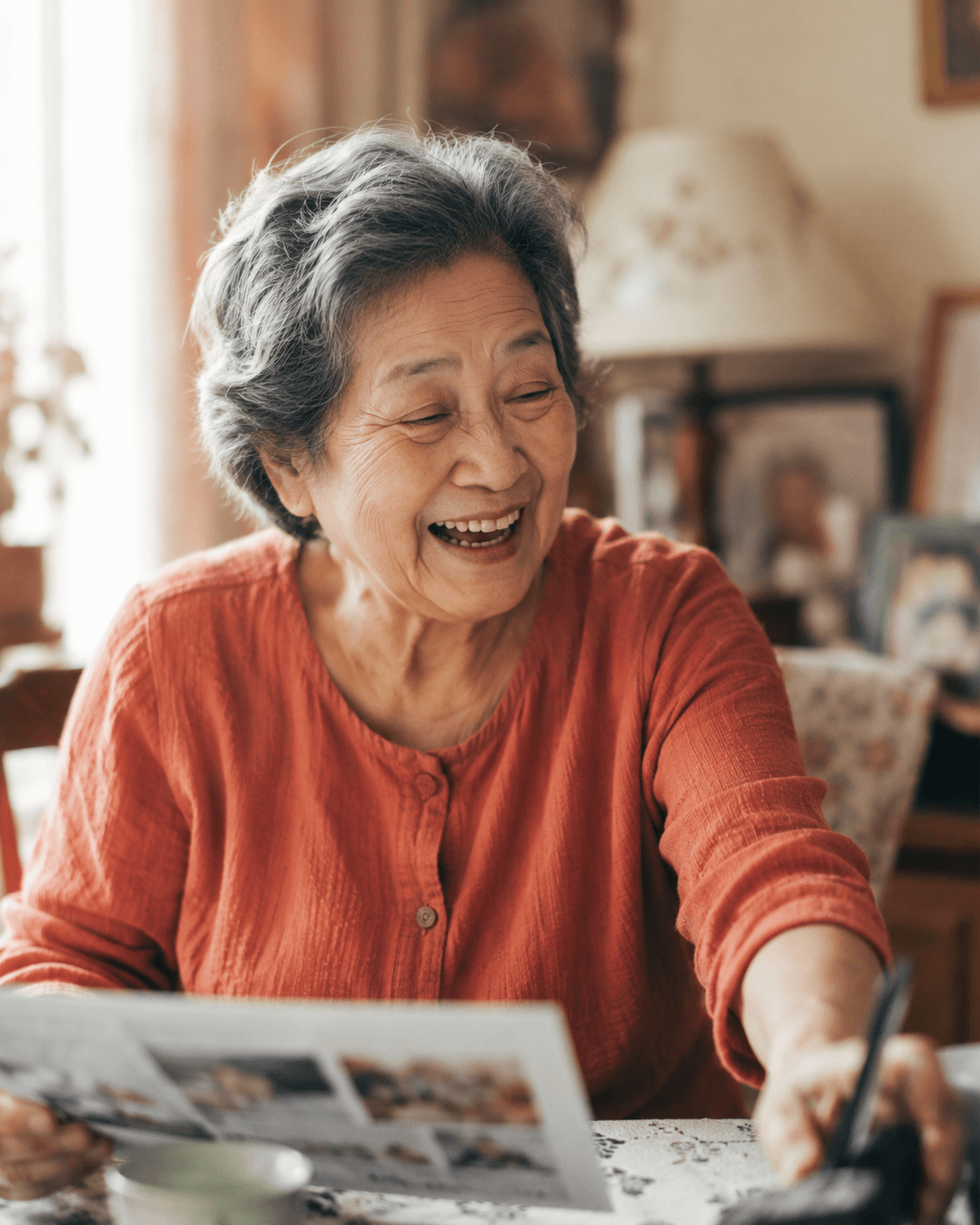 A grandmother laughing with delight as she looks over photos from her family's newsletter
